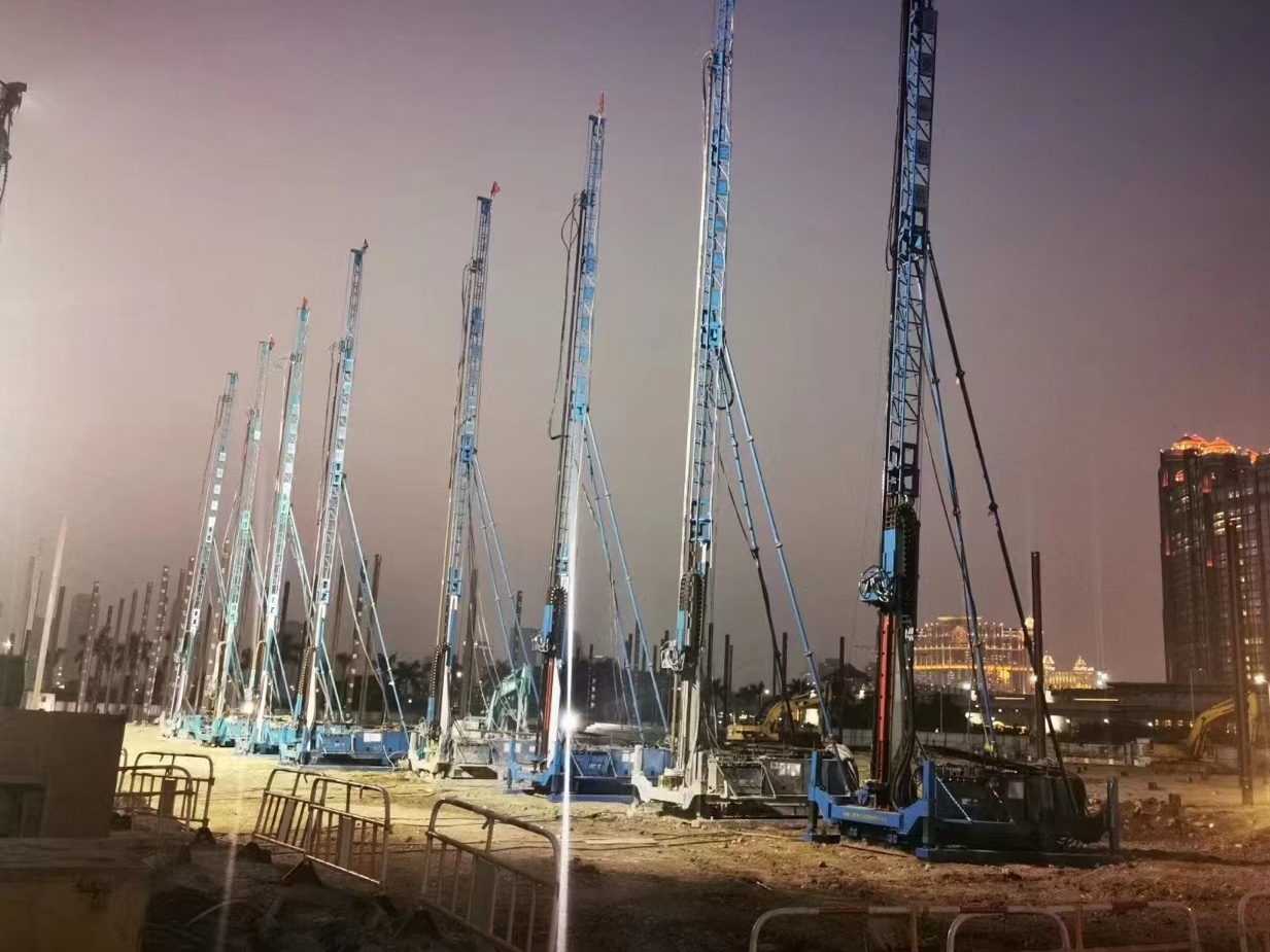 Row of blue jet grouting rigs working on a site at night
